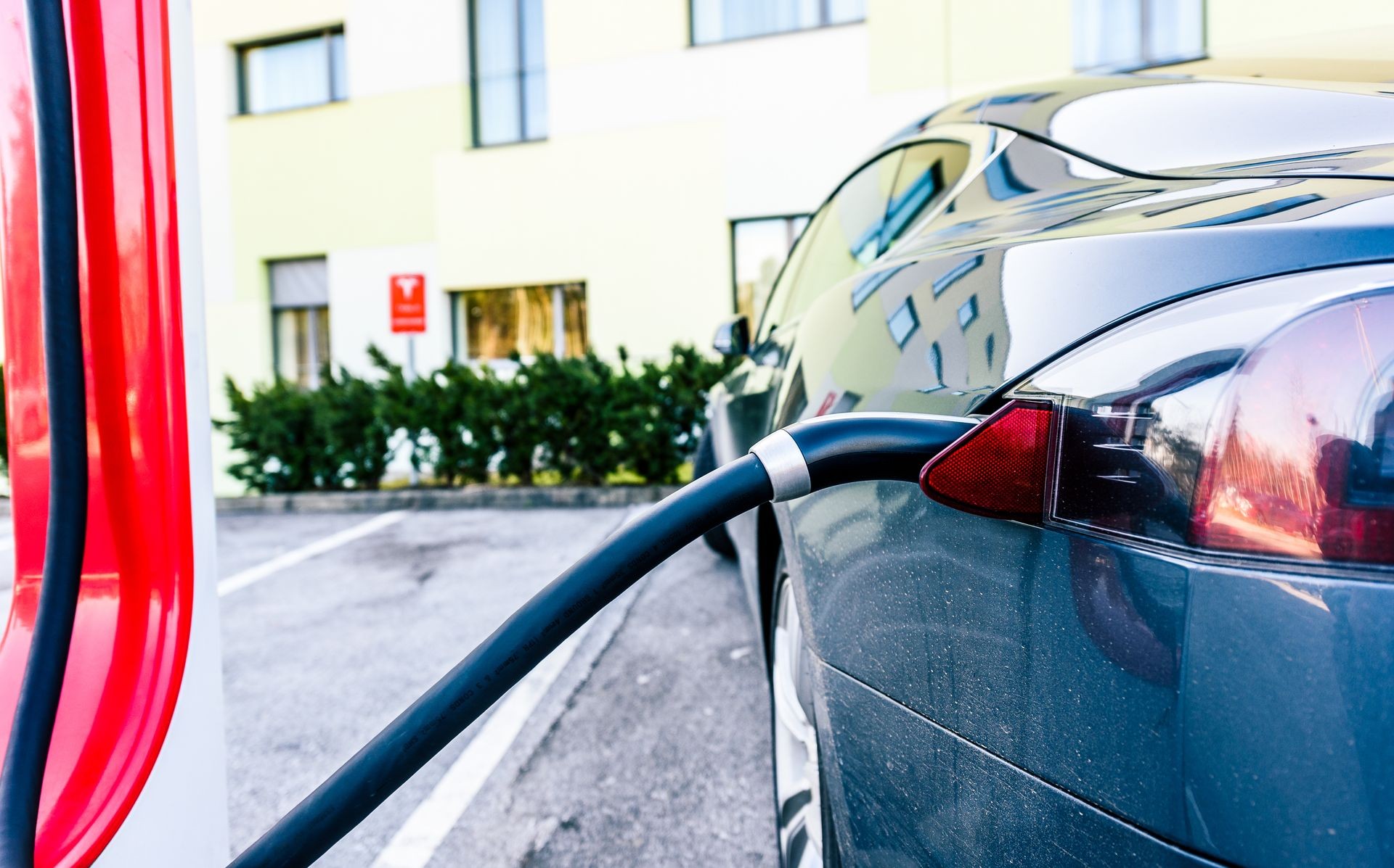 Black Tesla electric vehicle charging in parking lot